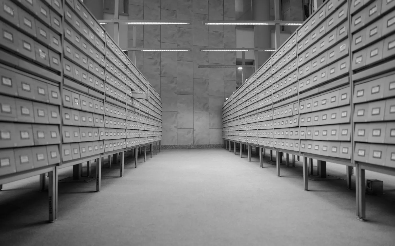 Two long rows of archive drawers in a grey records room